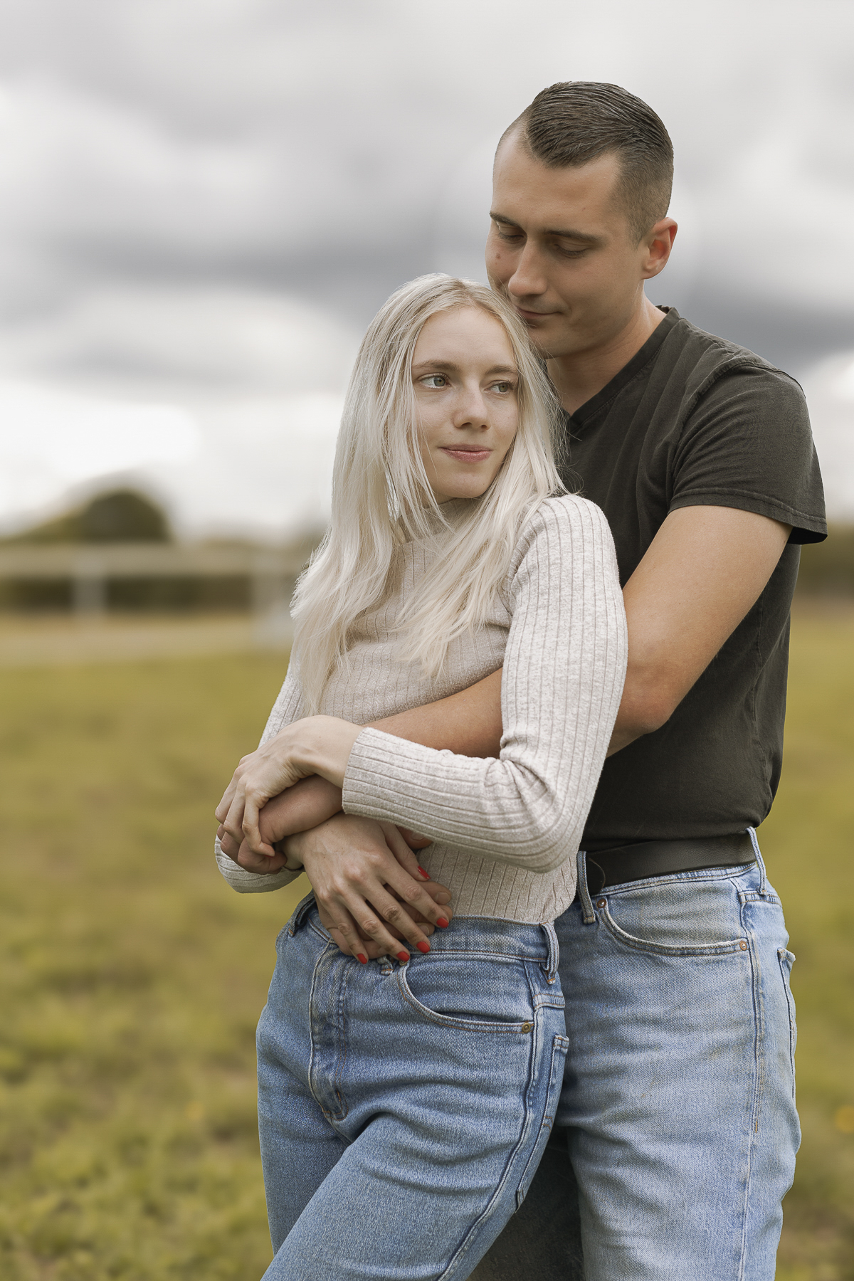 Ein Paar im Freien, er trägt sie in den Armen, er blickt sie an, sie schaut in die Ferne.