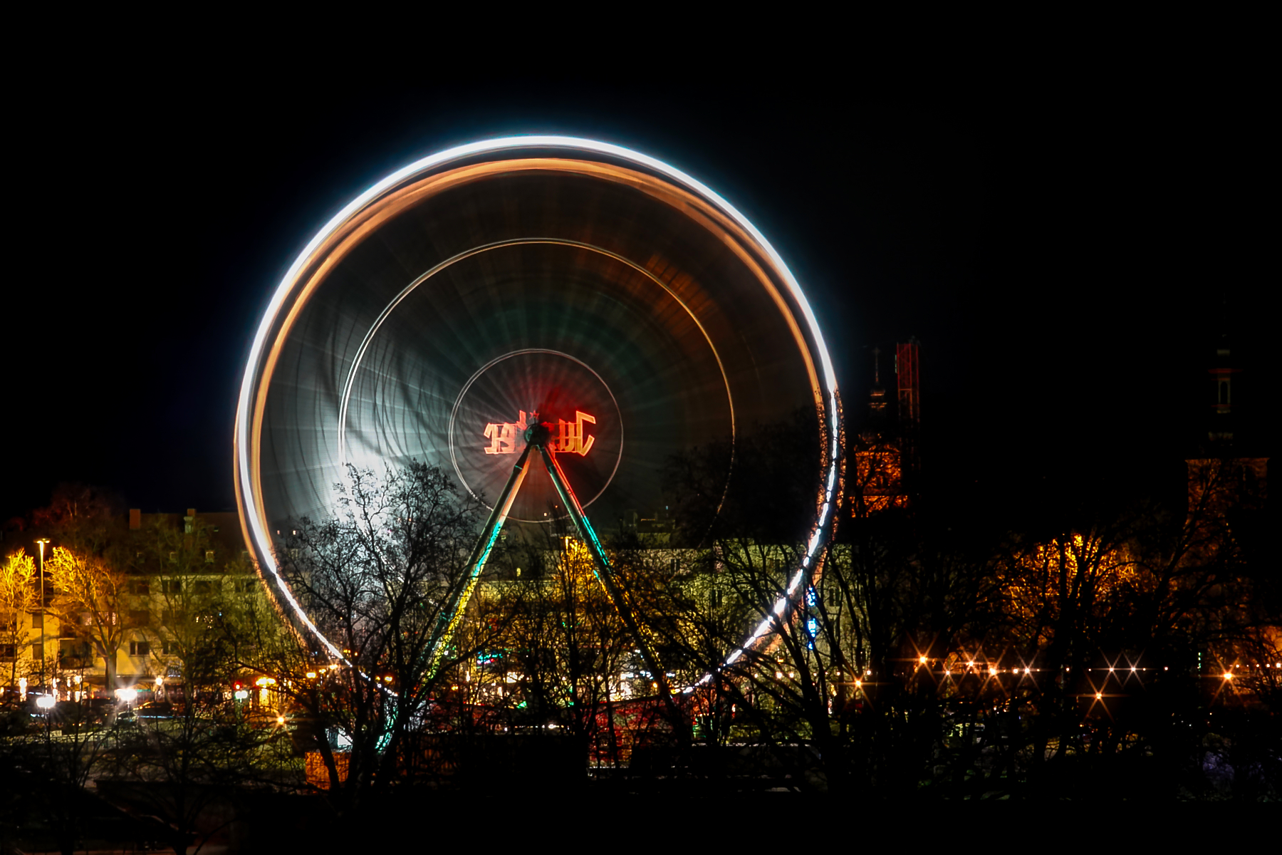 Langzeitbelichtung eines Riesenrads bei Nacht in Saarbrücken mit kreisförmigen Lichtspuren