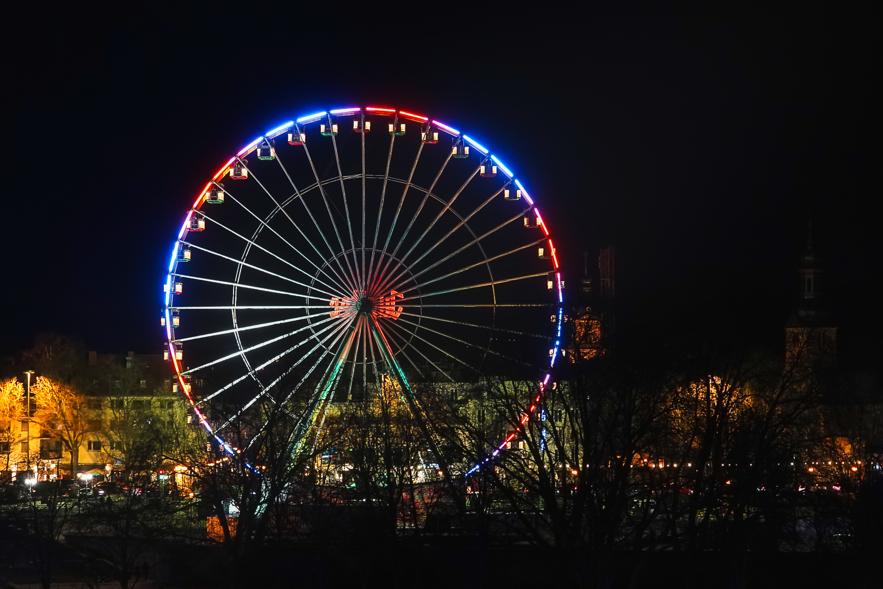 Beleuchtetes Riesenrad an der Saar bei Nacht in Saarbrücken mit farbigen Lichtern
